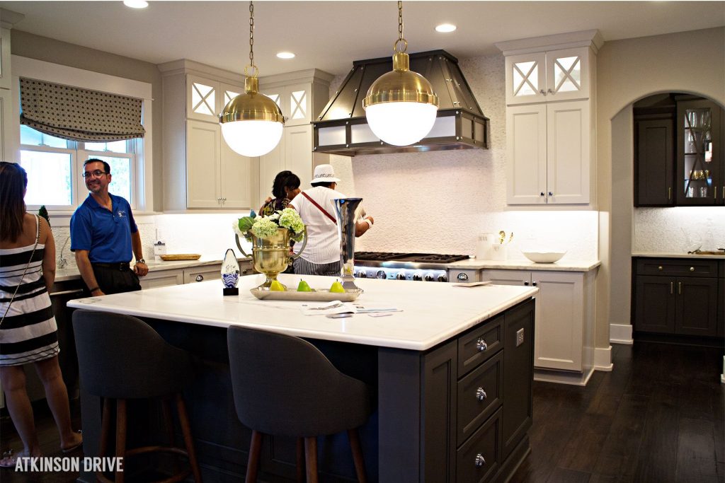 Home-a-Rama 2014: Beautiful kitchen featuring white cabinets and a dark island; gold lighting; and marble countertops | Atkinson Drive